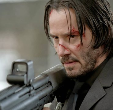Keanu Reeves playing John Wick holding a shotgun