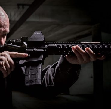 A picture of a guy holding an AR-15 with a Sightmark Ultra Shot mounted